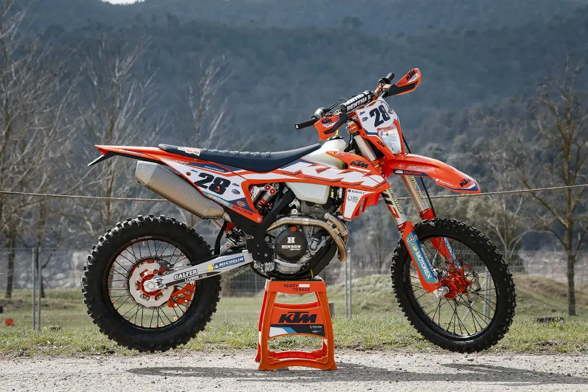 Una moto de cross naranja y blanca, modelo KTM, lista para la carrera, con el número 28.