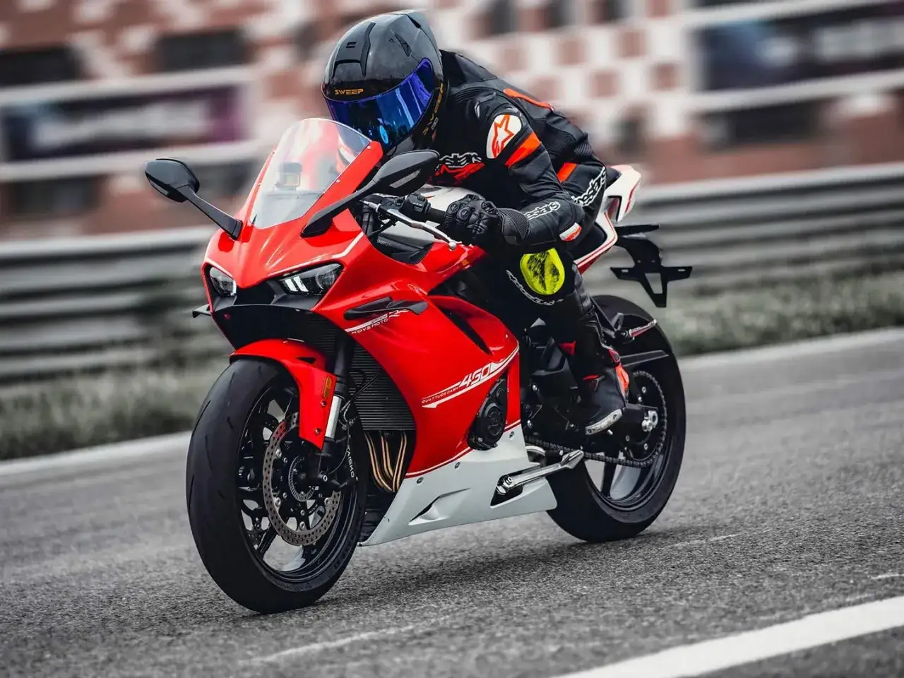 Piloto en una moto deportiva roja kove 450 rr en una pista.