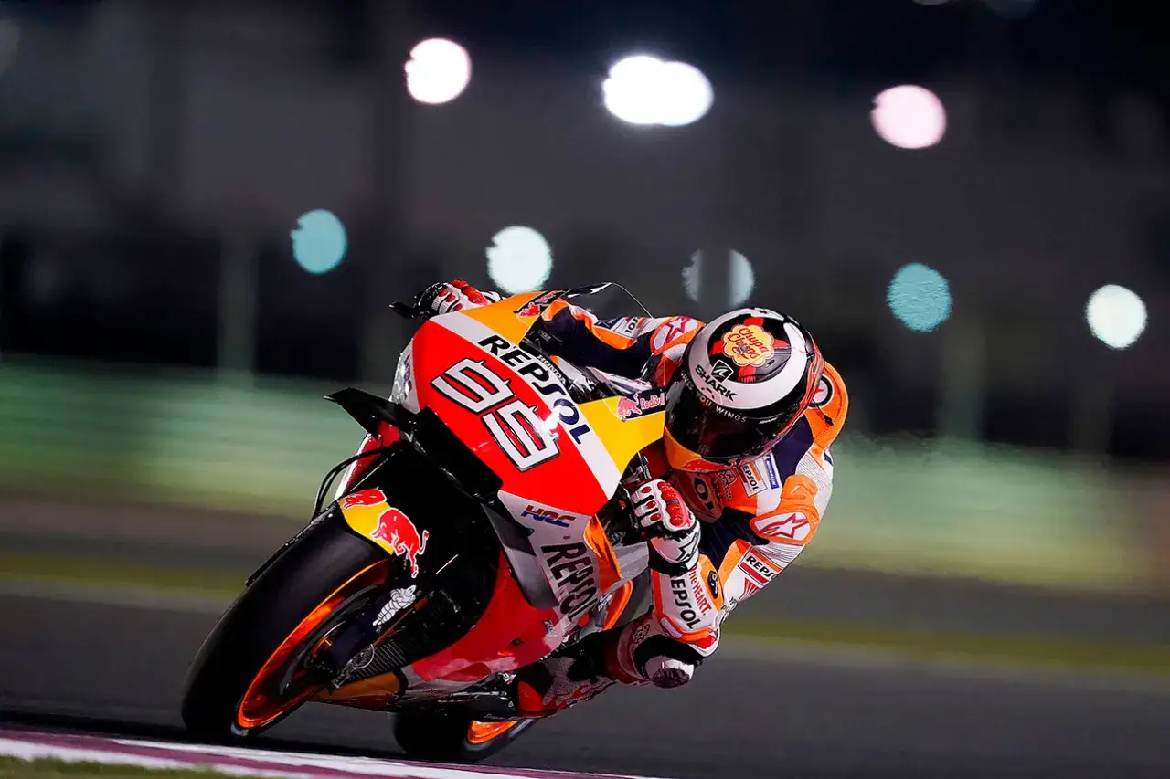 Jorge Lorenzo inclinado en su Honda Repsol, compitiendo bajo luces nocturnas.