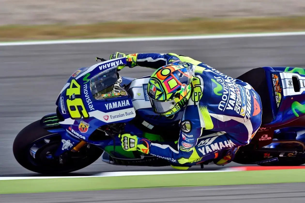 Valentino Rossi inclinado en su moto Yamaha azul y amarilla, número 46, en plena carrera.