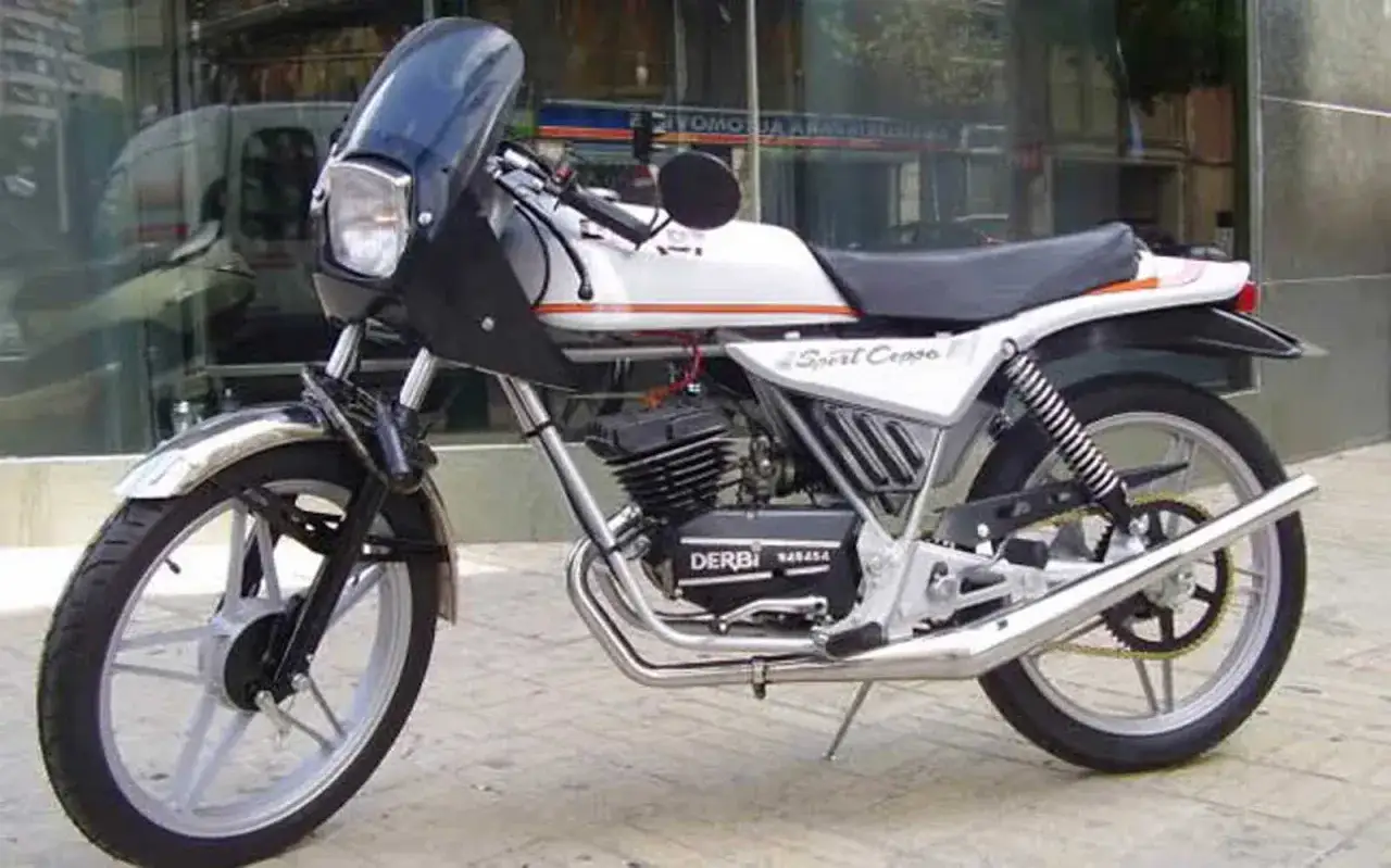 Clásica moto Derbi Sport Coppa, blanca con detalles naranjas, lista para rodar.
