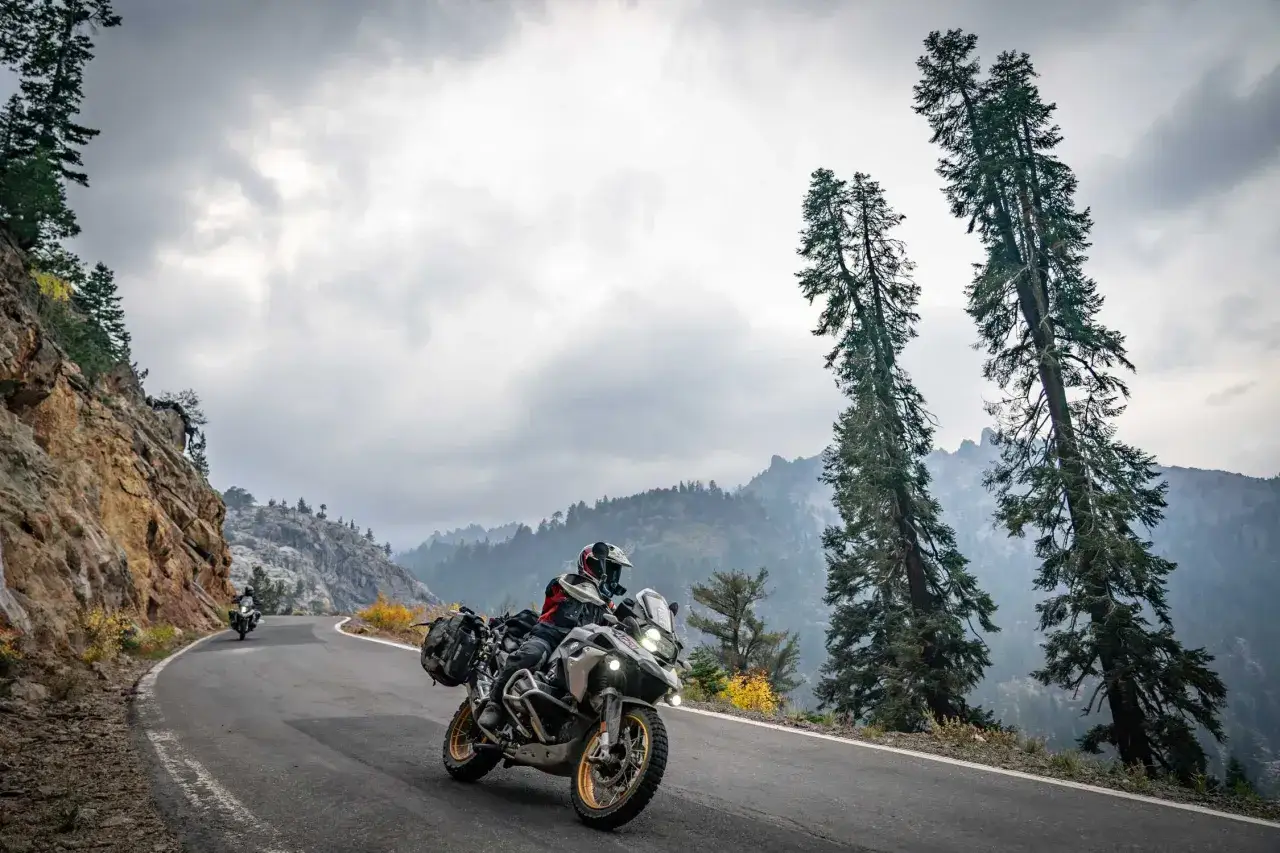 Motociclista en una carretera monta&ntilde;osa con motos BMW modelos, disfrutando de la aventura.