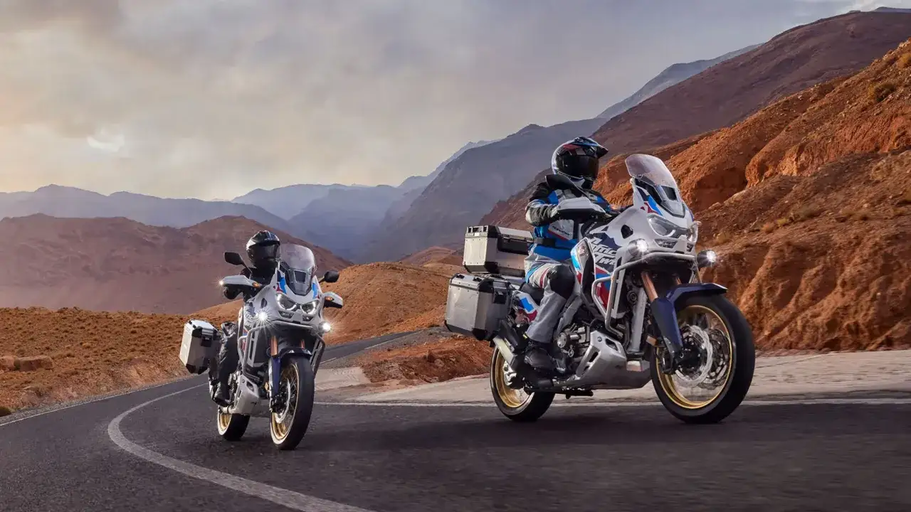 Dos motocicletas Honda Africa Twin recorren un camino desértico. Las opiniones sobre estas motos de aventura son excelentes para explorar paisajes como este.