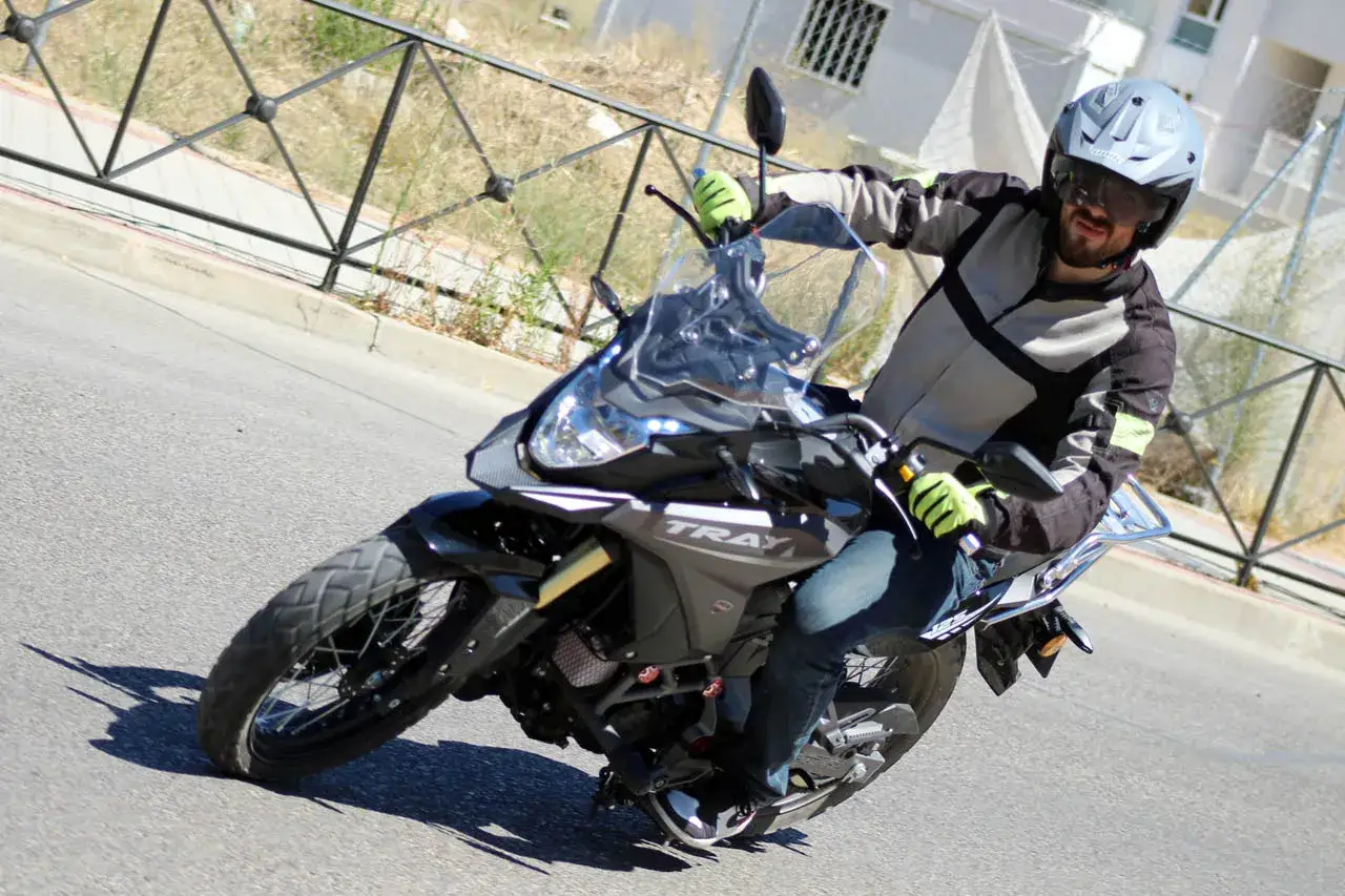Hombre con casco y chaqueta de moto, conduciendo una moto de 125cc por la carretera. ¡Sí, con una moto de 125 se puede ir por autopista!
