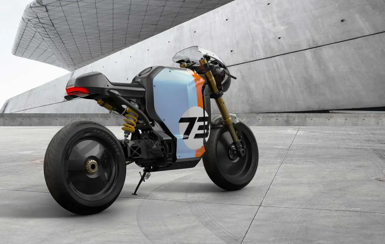 Una moto custom el&eacute;ctrica con dise&ntilde;o deportivo y n&uacute;mero 73 en la carrocer&iacute;a, estacionada en un entorno moderno de concreto.