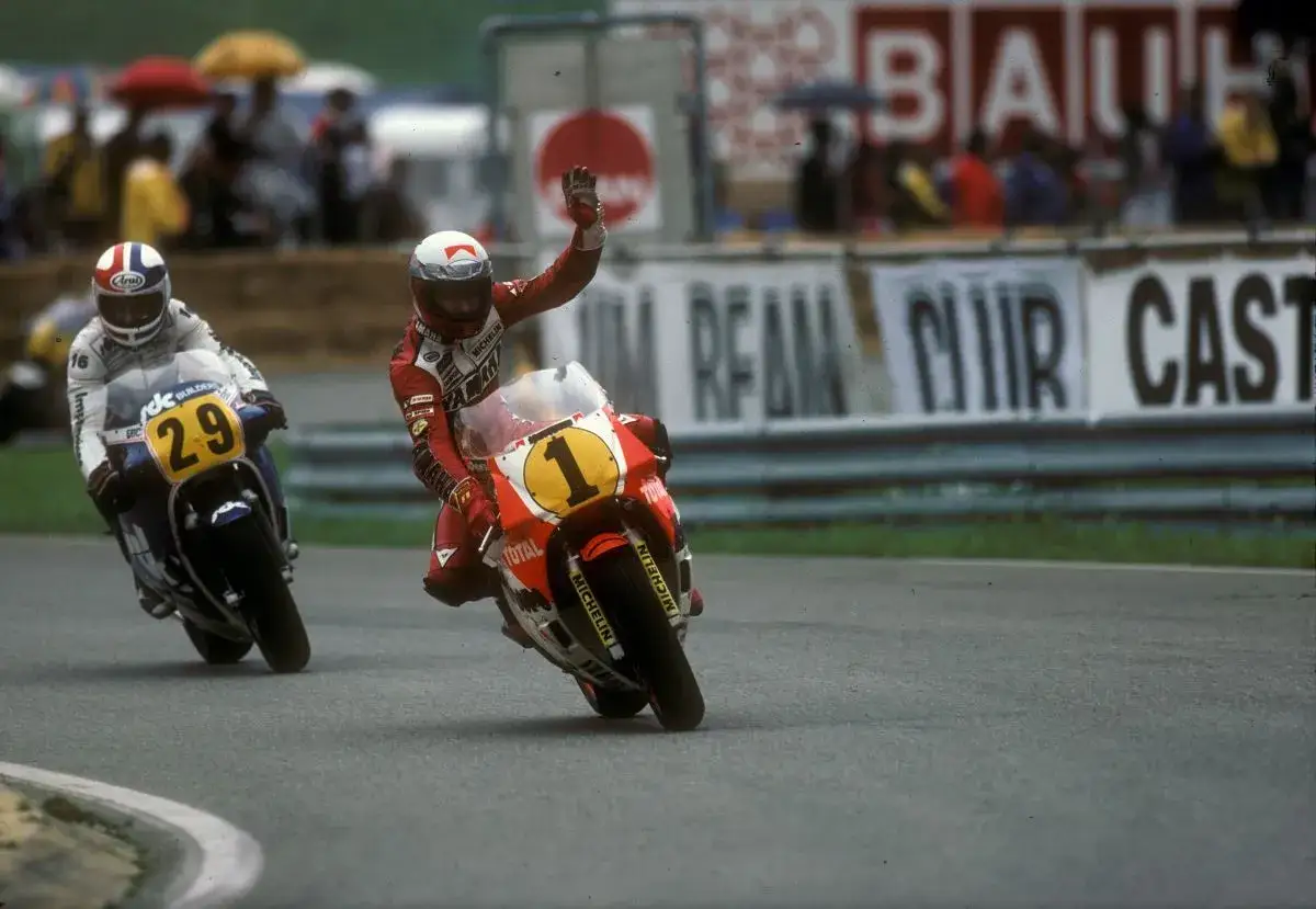 Eddie Lawson saluda mientras compite en una carrera de motos, con el n&uacute;mero 1 en su moto.