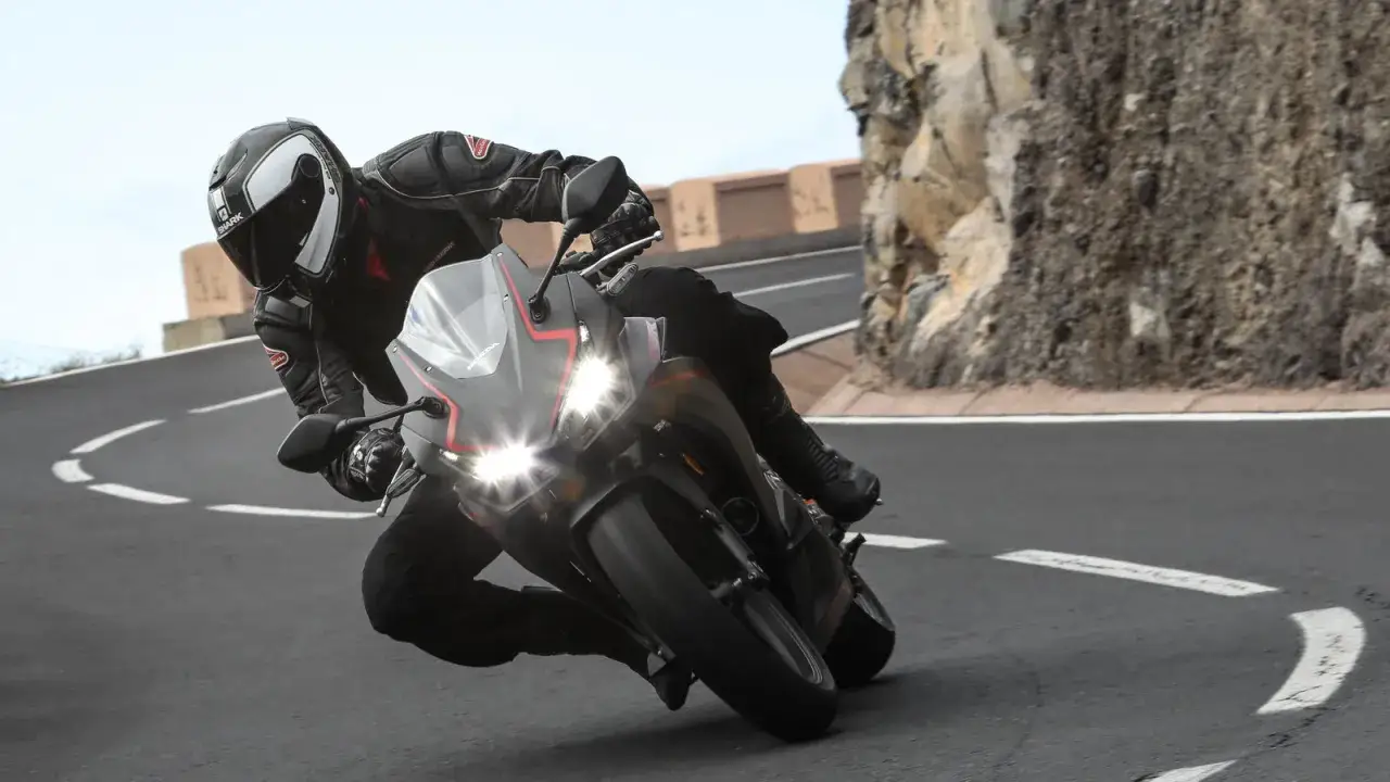 Motociclista con equipo completo inclinado en una curva cerrada con una Honda CBR500R. El peso de la moto es ideal para maniobrar.