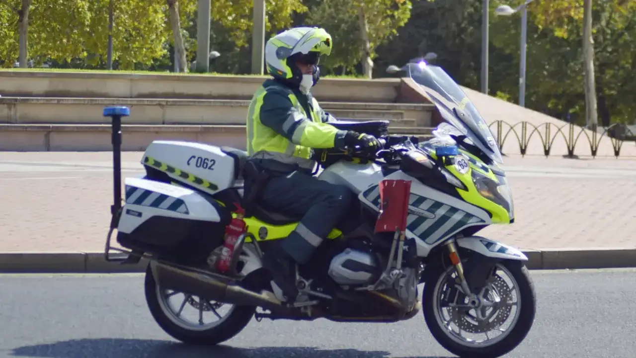Agente de tráfico en moto, con equipo de alta visibilidad, circulando con conduccion segura en moto.
