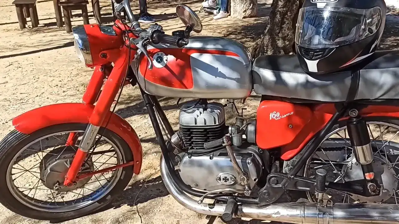 Una joya roja y plateada, una de las mejores motos clasicas, lista para rodar. Un casco negro descansa sobre el asiento.
