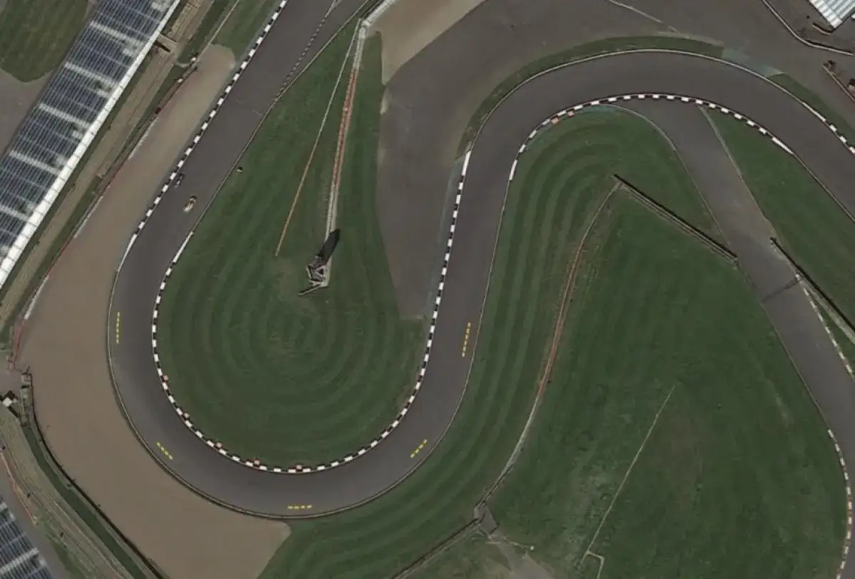 Vista a&eacute;rea de una curva en S de un circuito de carreras, con una moto de MotoGP prepar&aacute;ndose para un long lap.
