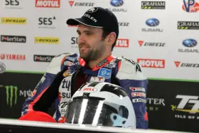 William Dunlop, piloto de motociclismo, sonríe con su casco de carreras y mono de competición.