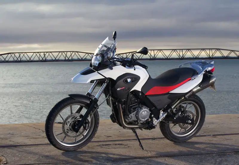 Moto BMW G 650 GS, ideal para el carnet A2, aparcada junto a un puente y el mar.