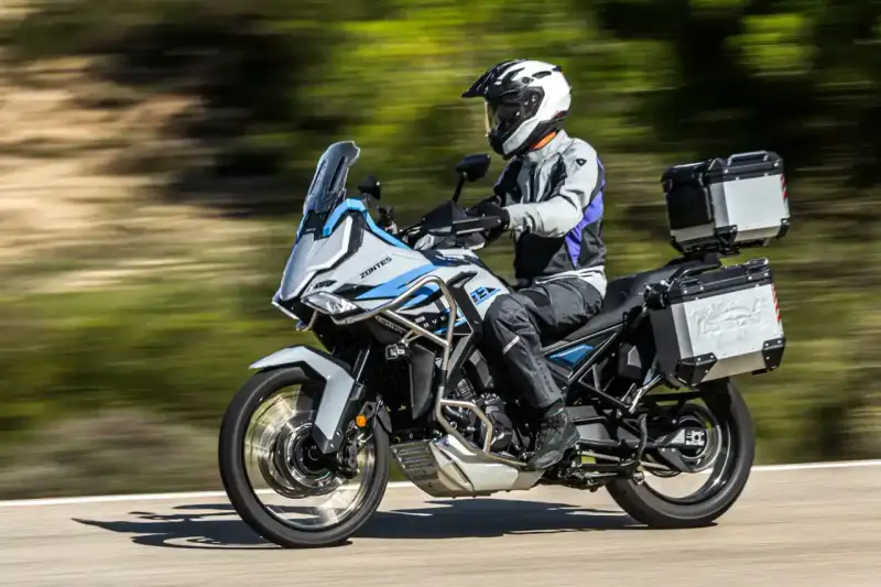 Motociclista con casco blanco y equipo de aventura sobre una moto Zontes, lista para explorar caminos. Motos adventure A2 perfectas para tu próxima travesía.