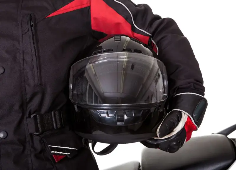Motociclista con chaqueta negra y roja, guantes y casco con visor transparente. El pinlock casco garantiza una visión clara.