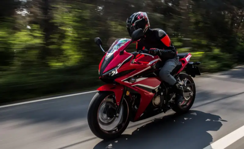 Motociclista en moto deportiva roja, disfrutando de la carretera con potencia máxima A2.