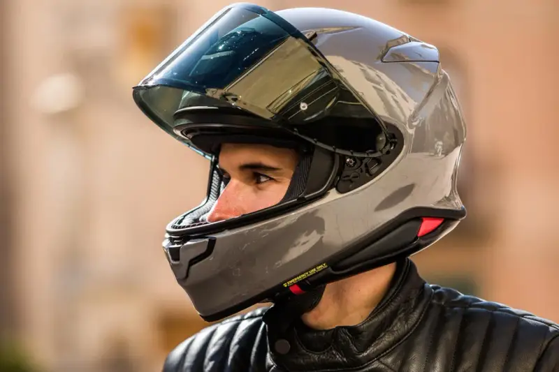 Hombre con casco de moto gris brillante. ¿Cuánto pesa un casco de moto? Este modelo parece ligero y aerodinámico.
