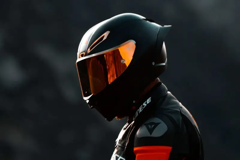 Motociclista con su primer casco de moto, visera naranja reflejando la luz.