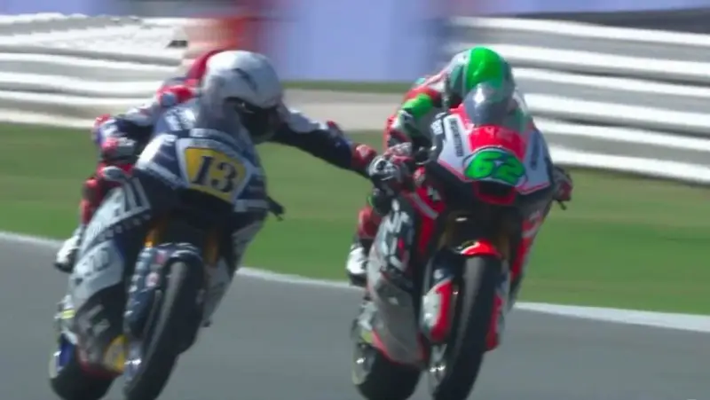 Dos pilotos de MotoGP compiten, uno con el número 13 y el otro con el 62. Romano Fenati, con el 13, intenta adelantar.